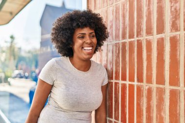 Afro-Amerikalı kadın gülümsüyor. Kendinden emin bir şekilde caddeye bakıyor.