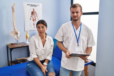 Young hispanic woman at physiotherapist appointment skeptic and nervous, frowning upset because of problem. negative person. 