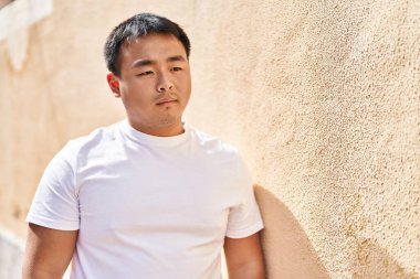 Young chinese man standing with relaxed expression at street