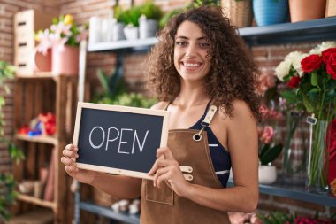 Hispanic woman with curly hair working at florist holding open sign smiling with a happy and cool smile on face. showing teeth. 