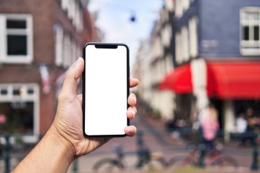 Elinde akıllı telefon tutan adam Amsterdam 'da beyaz boş ekran gösteriyor.