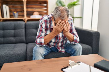 Psikoloji kliniğinde kanepede oturan yaşlı, gri saçlı adam.