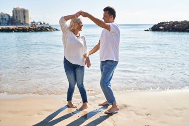 Middle age man and woman couple smiling confident dancing at seaside
