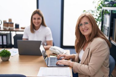 Mother and daughter business workers using laptop working at office