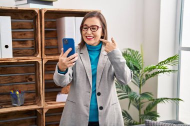 Orta yaşlı İspanyol kadın akıllı telefon kullanıyor. Video çekiyor. Gülümsüyor. 