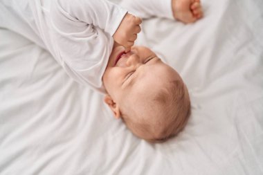 Sevimli bebek yatak odasında yatakta yatıyor.