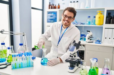 Genç İspanyol bilim adamı laboratuvarda sıvıyı ölçüyor.