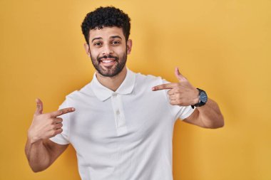 Sarı arka planda duran Arap adam kendine güveni tam görünüyor, kendini gururlu ve mutlu bir şekilde gösteriyor.. 