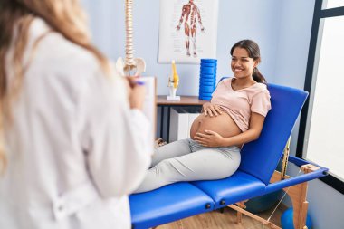 Genç Latin kadın hamile hasta klinikte fizyoterapi seansı yapıyor.