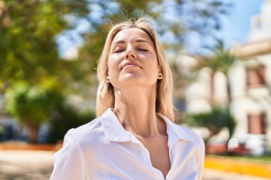 Young blonde woman smiling confident breathing at park