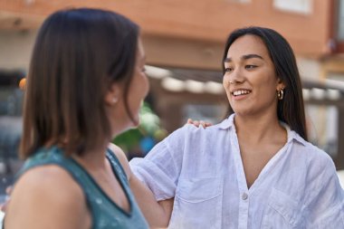 Two women mother and daughter smiling confident standing together at street