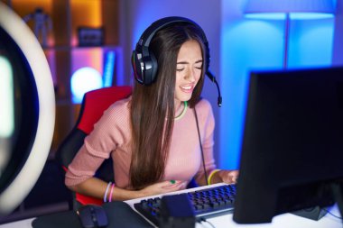 hazımsızlık, acı verici hastalıklar yüzünden karın üstü bilgisayar oyunu oynayan genç İspanyol kadın. Ağrı kavramı. 