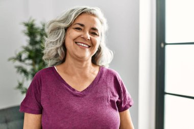 Orta yaşlı, kır saçlı, mutlu gülümseyen bir kadın..