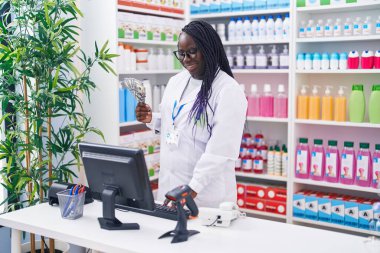 Afro-Amerikalı kadın eczacı gülümseyerek eczanede dolar sayıyor.