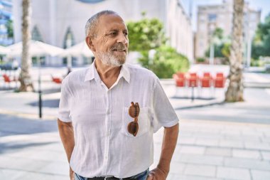 Kıdemli adam sokakta kendinden emin gülümsüyor.