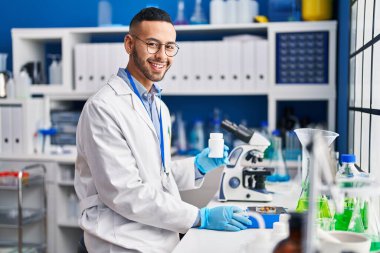 African american man scientist smiling confident weighing pills at laboratory