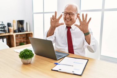 Ofiste çalışan son sınıf öğrencisi bilgisayarla dokuz numarayı gösterip işaret ederken kendinden emin ve mutlu bir şekilde gülümsüyor.. 