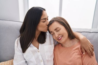 Two women mother and daughter sitting on sofa together at home