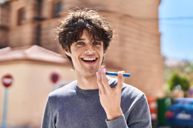 Genç İspanyol adam gülümsüyor. Kendine güveniyor. Sokakta akıllı telefondan konuşuyor.