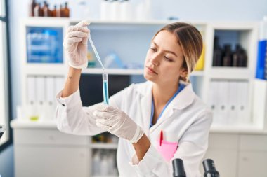 Laboratuvarda test tüpüne sıvı döken genç İspanyol bilim kadını.