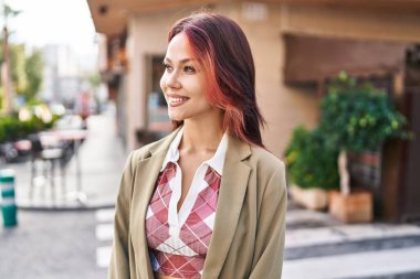 Beyaz kadın gülümsüyor. Kendinden emin. Caddenin kenarına bakıyor.