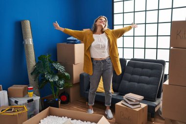 Yeni evinde kollarını açmış kendine güvenen genç sarışın kadın.