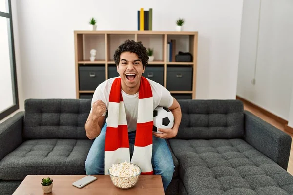 stock image Young hispanic man watching soccer match and supporting team at home.