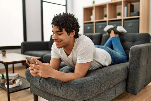 Ung Latinamerikan Man Med Smartphone Liggande Soffan Hemma — Stockfoto