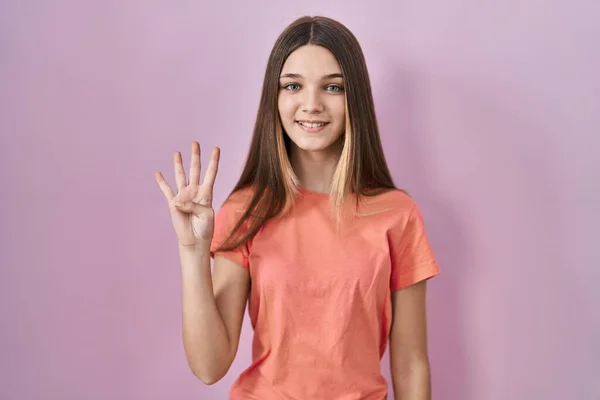 少女站在粉红的背景上 用四号手指指指着 面带微笑 自信而快乐 — 图库照片