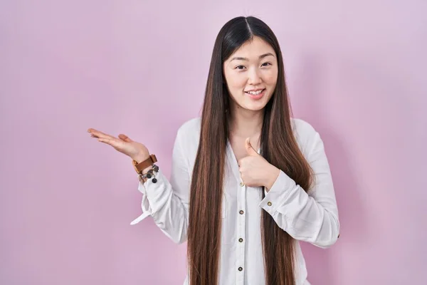 Chińska Młoda Kobieta Stoi Nad Różowym Tle Pokazując Dłoń Dłoni — Zdjęcie stockowe
