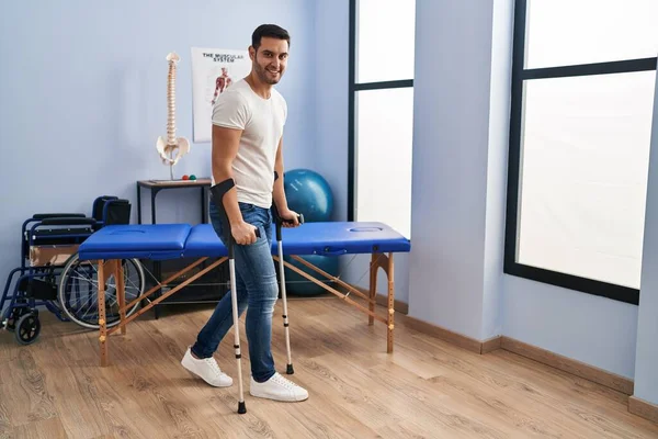 Young Hispanic Man Injured Physiotherapy Patient Using Crutches Walking Rehab — Stockfoto