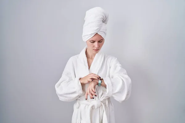 金发女人穿着浴衣检查腕表上的时间 放松而自信 — 图库照片