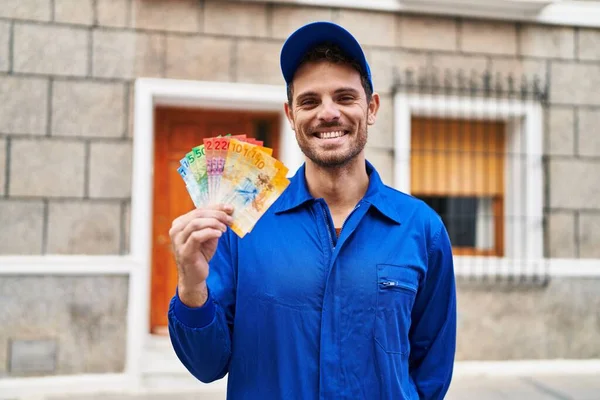 Young Hispanic Man Wearing Handyman Uniform Holding Swiss Francs Looking — Stock Photo, Image