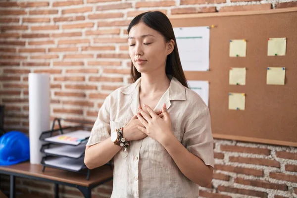 stock image Chinese young woman working at the office doing presentation smiling with hands on chest with closed eyes and grateful gesture on face. health concept. 