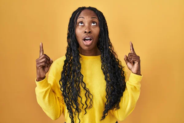 African Woman Standing Yellow Background Amazed Surprised Looking Pointing Fingers — Stock Photo, Image