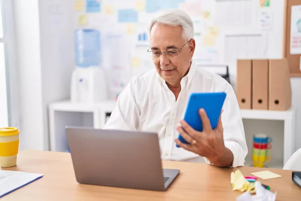 中年白发男性商人在办公室使用触摸板和笔记本电脑 — 图库照片