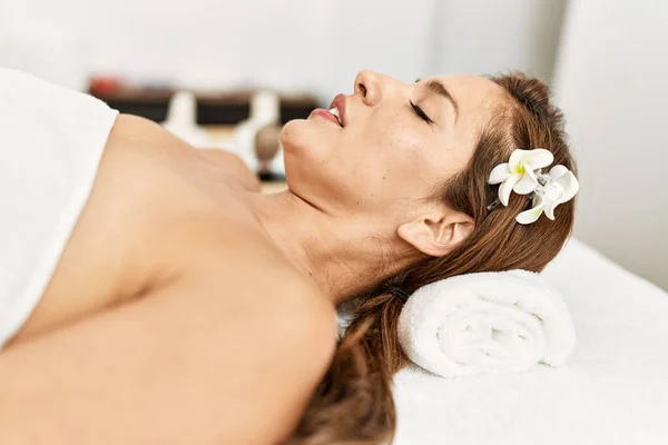 Young latin woman relaxed lying on massage table