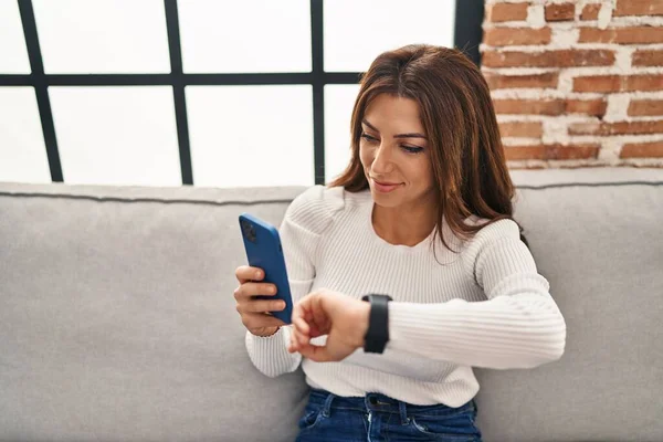 Jonge Spaanse Vrouw Met Behulp Van Smartphone Kijken Horloge Thuis — Stockfoto
