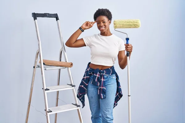 Africano Americano Mulher Segurando Rolo Pintor Sorrindo Apontando Para Cabeça — Fotografia de Stock