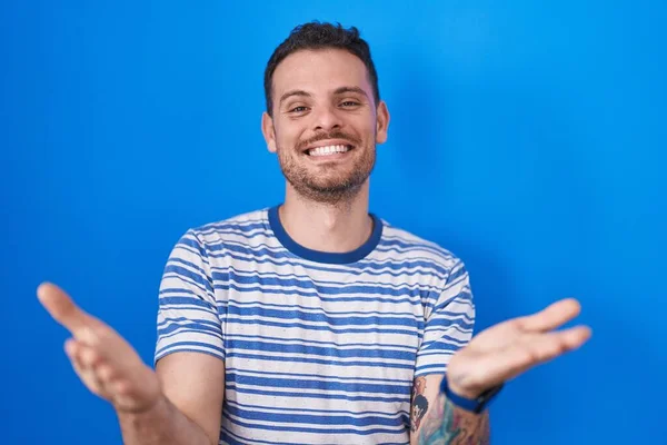 Jonge Spaanse Man Staat Blauwe Achtergrond Glimlachend Vrolijk Het Aanbieden — Stockfoto