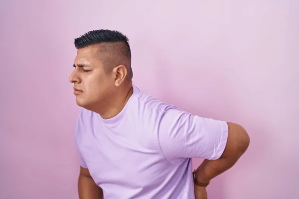 Молодой Латиноамериканец Стоя Розовом Фоне Страдает Боли Спине Касаясь Спины — стоковое фото