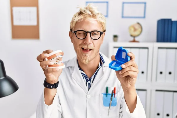 Young Blond Dentist Man Working Dentist Clinic Holding Brackets Aligner — Stok fotoğraf