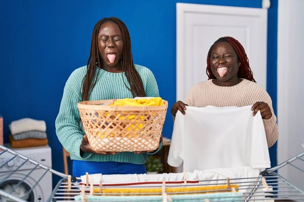 Две Африканки Вешают Одежду Бельевой Верёвки Торчащей Языком Довольные Смешным — стоковое фото