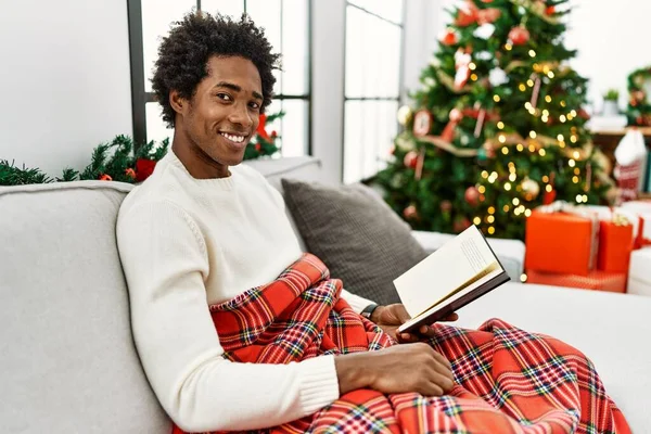 Joven Hombre Afroamericano Leyendo Libro Sentado Sofá Por Árbol Navidad — Foto de Stock