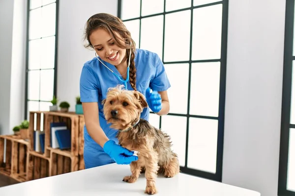 年轻美丽的惊慌失措的女兽医在家里用听诊器检查狗 — 图库照片
