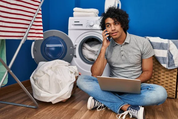 Mladý Hispánec Pomocí Notebooku Mluvení Smartphone Čeká Pračku Prádelně — Stock fotografie