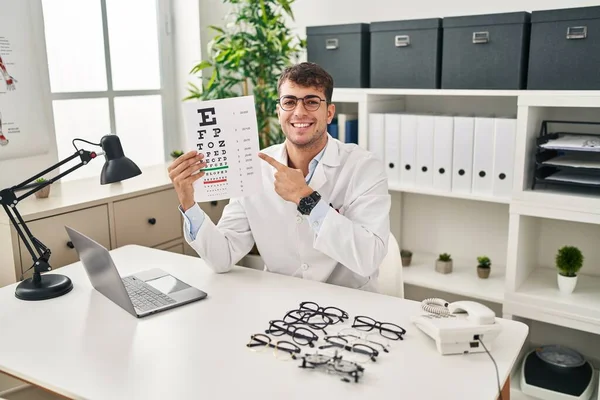 Jonge Spaanse Man Werkt Oogheelkunde Kliniek Glimlachend Blij Wijzend Met — Stockfoto