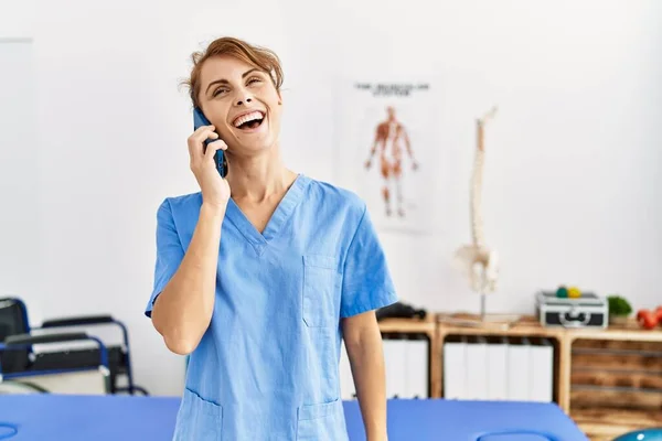 Jovem Fisioterapeuta Caucasiana Menina Sorrindo Feliz Falando Smartphone Clínica — Fotografia de Stock