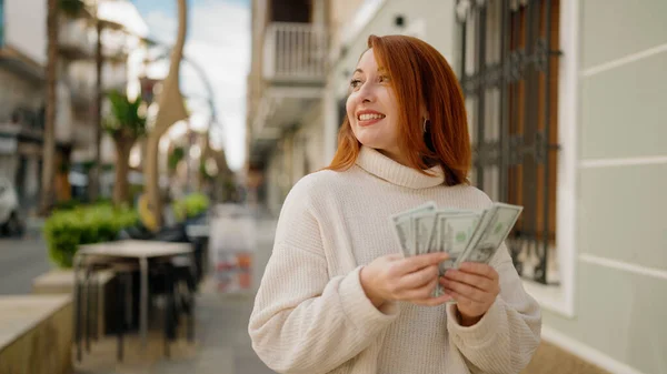 Молодая Рыжая Женщина Улыбается Уверенно Считая Доллары Улице — стоковое фото
