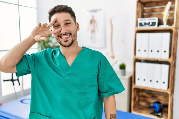 Young Physiotherapist Man Working Pain Recovery Clinic Doing Peace Symbol — Stockfoto